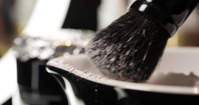 Close-up of a shaving brush swirling in a bowl of lather with a blurred background