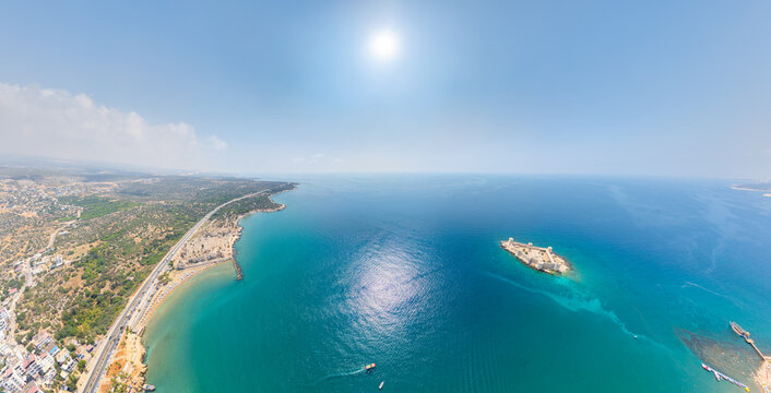 Kizkalesi, Mersin, Turkey. Expansive aerial panorama of legendary Maiden Castle island, surrounded by deep blue Mediterranean Sea, sandy shores and modern resort. Aerial view