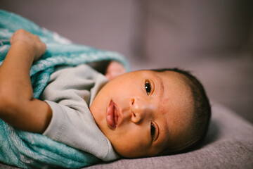 Close up face of newborn baby black boy at home in blanket