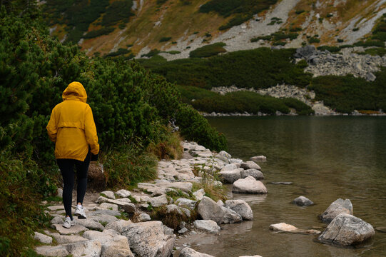 Woman in yellow jacket hiking on rocky mountain lake in Zakopane