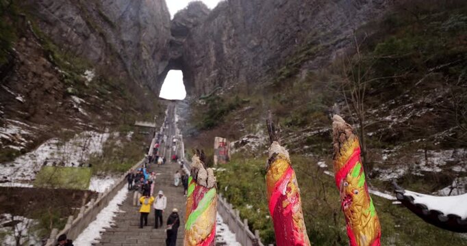 Selective focus on thick, giant joss sticks smoldering at Tianmen Mountain. Wisps of white incense smoke rise gently against blurred background of 999 Steps and Heaven's Gate arch.