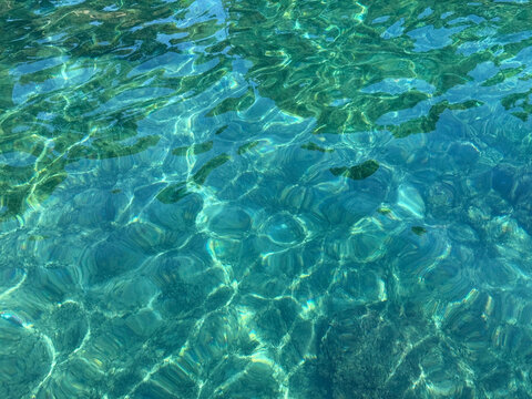 Crystal clear turquoise sea water with sun glare.