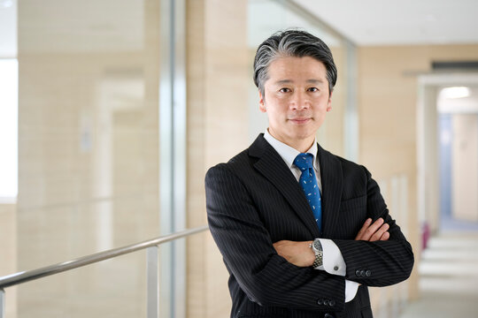 オフィスの廊下で笑顔の50代男性ビジネスマン