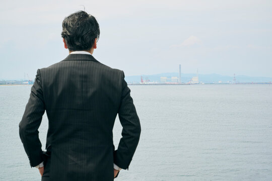 海を見渡す50代男性ビジネスマンの後ろ姿