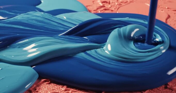 Close-up of vibrant blue and coral paint mixing on a textured canvas, showcasing artistic creativity