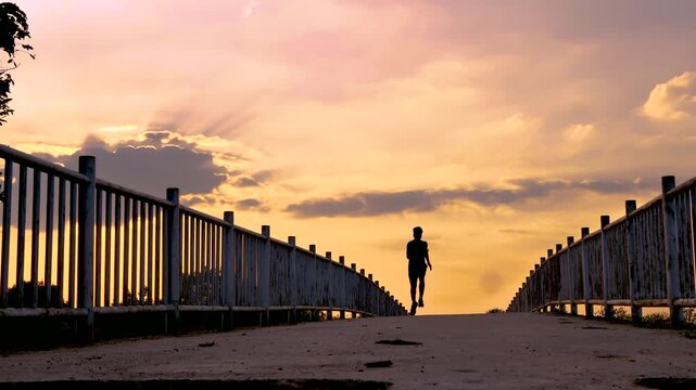 Silhouette of young man running sprinting on road. Fit runner fitness runner during outdoor workout with sunset background. 4K