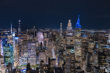Night aerial view of Midtown Manhattan skyline with illuminated skyscrapers and dense urban city...