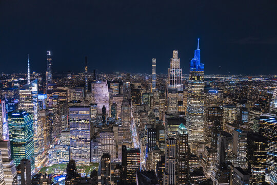 Night aerial view of Midtown Manhattan skyline with illuminated skyscrapers and dense urban city lights in New York City USA