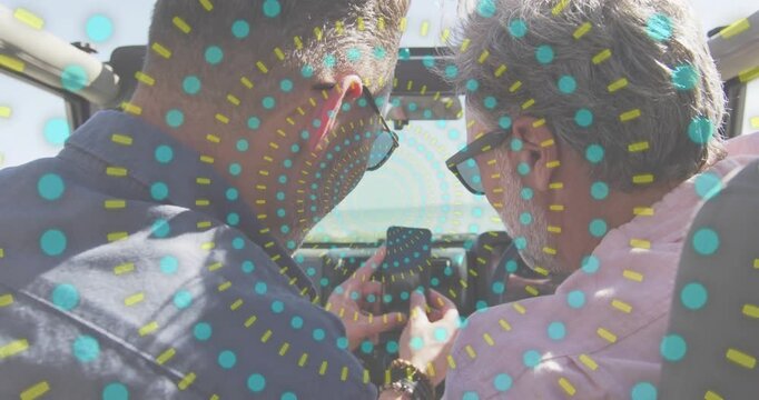 Vertical video: Leaning two men with shades checking lit phone, smiling in convertible dot overlay