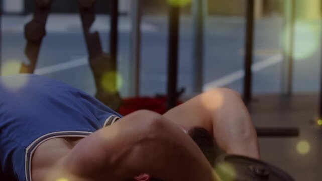 Camera revealing man lying on bench, gripping dumbbell, doing pullover for fitness with bokeh