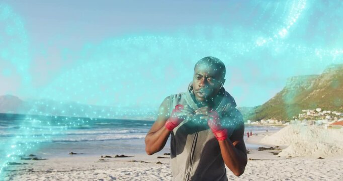 Vertical video: Shadowboxing man gray hoodie red hand wraps on sand training as blue flow sweeping