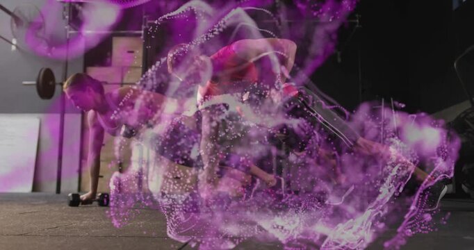Mid-adult pair training plank at gym, man initiating twist, woman bracing dumbbells, purple swirl