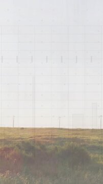 Vertical video: Sunny field staying, sun shifting causing lens flare, grid and poles for film
