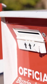 Young Man Places Mail-In Ballot Envelope in Official Voting Drop Box Beside Drop Ballot Here Sign Vertical