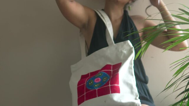 Woman presenting a custom canvas tote bag, showcasing a unique design pattern for sustainable fashion and everyday lifestyle accessories from a small business