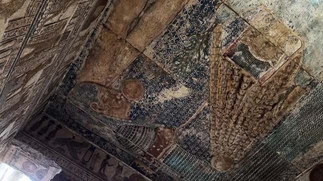 Low angle view of the remarkably preserved blue astronomical ceiling and wall reliefs featuring celestial figures and symbols inside the Temple of Hathor in Dendera