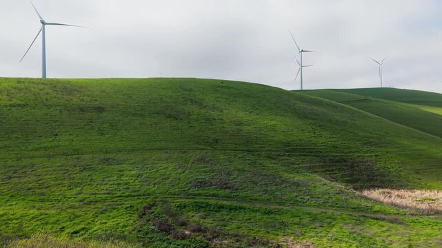 Ascending drone footage of spinning wind turbines at Altamont Pass near Dublin, CA. Useful for green energy, documentary, and California industrial media projects.