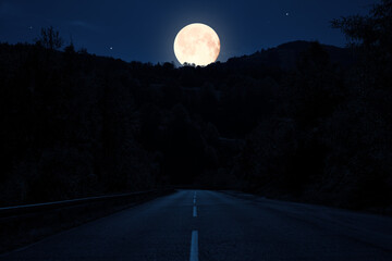 Moonlit countryside two lane road at night. © astrosystem
