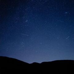 Fototapeta premium Milky way stars and constellations with landscape silhouettes photographed from a dark countryside location.