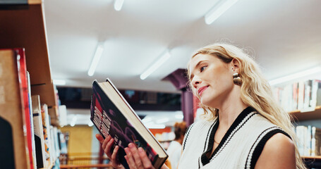 Obraz premium Student, girl and reading a book at bookshelf for college research, microbiology and knowledge. University, person and check course resources in library for thesis citation, science info and learning