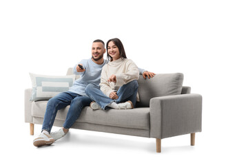 Young couple watching TV on grey sofa against white background