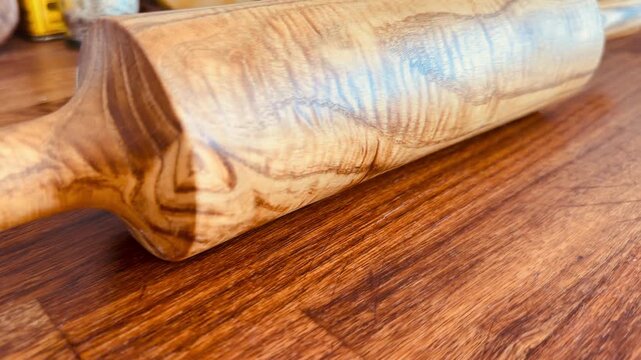 Luxury handmade rolling pin made of premium walnut wood on an oak panel. Professional kitchen tool for dough. High-end wooden kitchenware with natural grain texture, minimalist background.