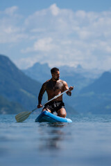 Summer tourism paddleboarding adventure on mountain Alps lake. Summer freedom and travel. Summer tourism during calm water vacation. Summer tourism lifestyle with nature.