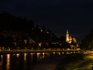 Obraz premium Night view of the city of Salzburg, Austria, highlighting the illumination of its historical monuments along the Salzach River