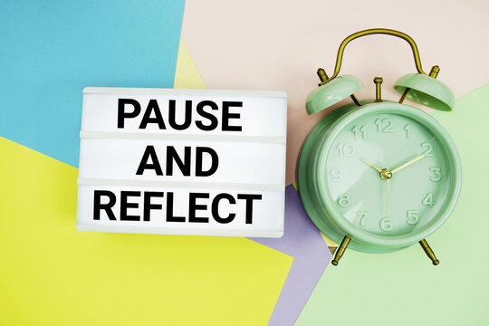 Pause and Reflect text in lightbox with alarm clock on pastel background