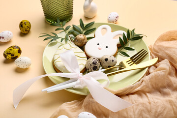 Fototapeta premium Beautiful table setting with sweet cookies, leaves and Easter eggs on beige background, closeup