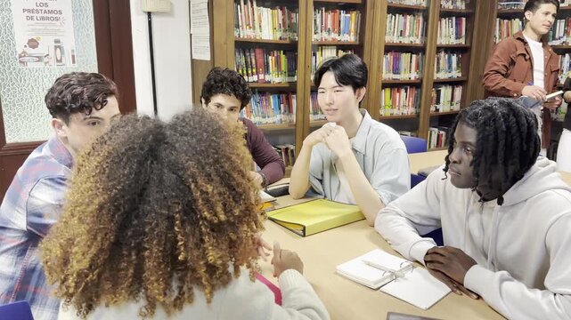 Young multiracial college students collaborating and discussing a project around a table in the library