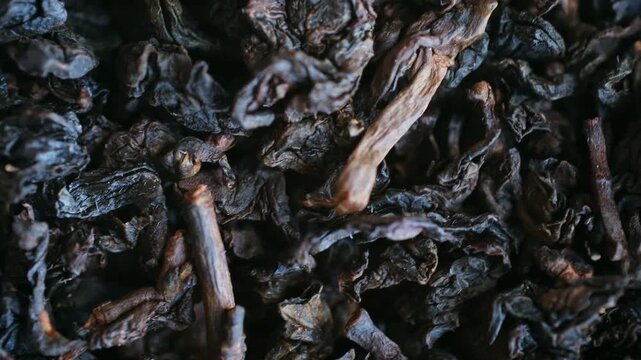 Extreme close up fermented, dry black tea leaves rotating slowly, revealing intricate textures, details of organic herbal ingredient used for making a traditional hot beverage. Gabba tea rotating