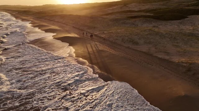 People walk along Playa del Barco beach on the Atlantic Ocean during sunset in Santa Teresa Park in Uruguay.