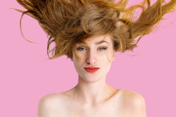 Naklejka premium a joyful young woman with strawberry blonde hair lying on a white surface. She is captured in a moment of genuine laughter, with her eyes squinted shut and a wide, bright smile revealing white teeth. 