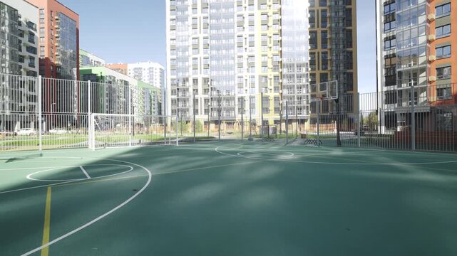 Basketball court with rubber coating positioned against densely built residential district. Sports environment integrated into cityscape