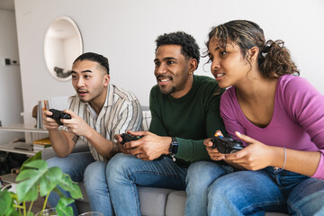 Diverse young adults having fun together, playing video games with controllers in a modern living room © Koldo_Studio