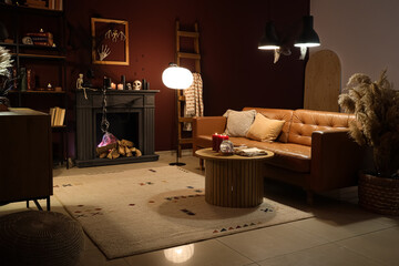 Fototapeta premium Interior of dark living room decorated for Halloween with sofa, fireplace and glowing lamps
