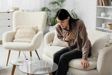 Fototapeta premium Young worried woman having panic attack on sofa at home