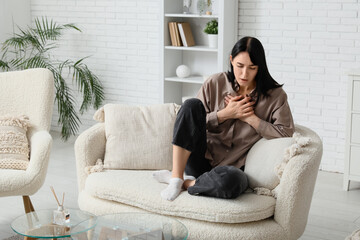 Obraz premium Young worried woman having panic attack on sofa at home