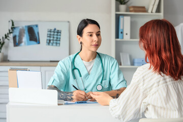Fototapeta premium Tattooed female doctor working with patient at table in clinic