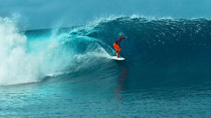 CLOSE UP: Fearless pro surfboarder rides a glassy emerald ocean wave in Tahiti. © helivideo