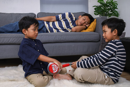 Two Young Boys Fight for Megaphone while His Dad Sleep on Coach at Home