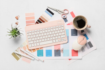 Fototapeta premium Computer keyboard with mouse, cup of coffee, stationery and color palettes on white background, top view