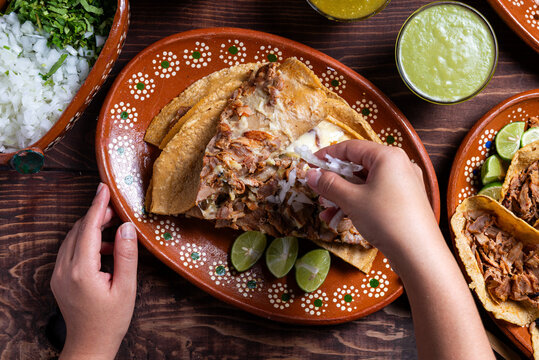 Traditional Delicious gringa Plate with Hand Garnishing with Onion Overhead Food