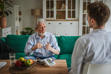 Elderly man discussing healthcare with doctor during home visit