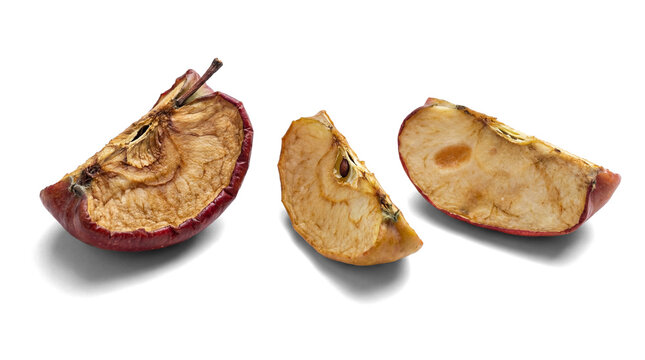 three desiccated apple slices, presented against a white, opaque transparent background, highlighting their wrinkled texture and aged appearance.