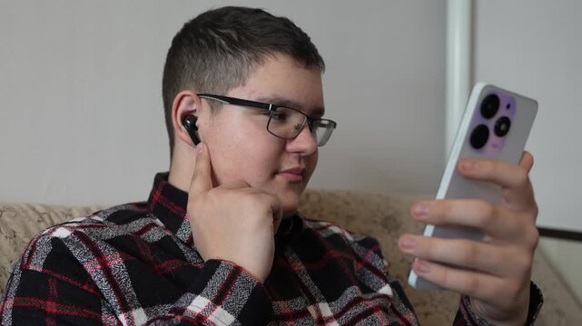 Smiling teenager with headphones using smartphone in shopping mall, young man listening to music, texting, chatting online, modern digital lifestyle, social media and youth technology concept.