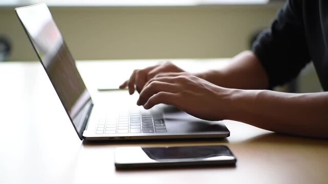Man Typing on Laptop at Desk.