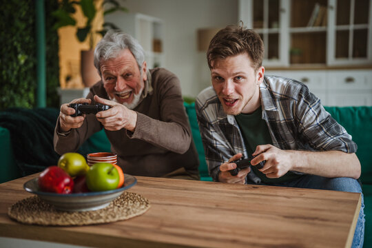 Grandfather and grandson enjoying video gaming together at home