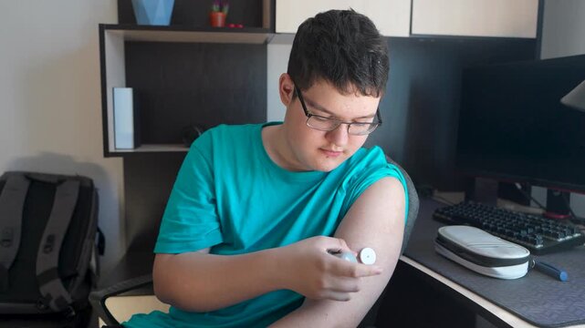 Measurement of blood glucose with the help of mobile applications and sensors. The young man installs a sensor to measure blood glucose.